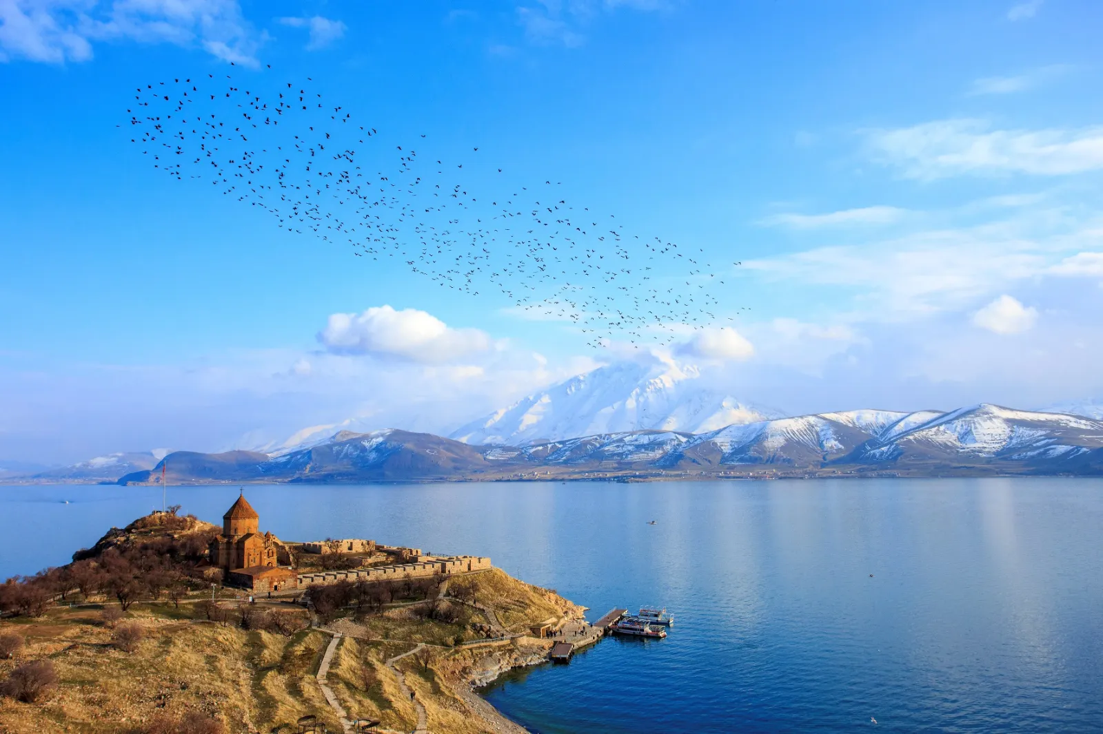 Der Vansee in der Osttürkei ist zusammen mit einer Landzunge im Vordergrund und dem Bergpanorama im Hintergrund zu sehen.