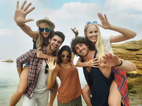 Eine Reisegruppe junger Menschen posiert und lacht in die Kamera.