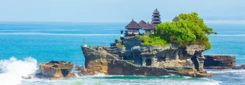 Die Tempelanlage Tempel Pura Tanah Lot auf einem Felsen in Bali, umgeben von türkisfarbenem Wasser.
