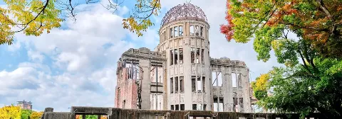 Die Ruine im Friedenspark in Hiroshima, umgeben von grünen Bäumen.