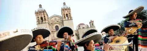 Mexikanische Musiker sind in traditioneller Tracht mit großen Hüten gekleidet und musizieren auf einem öffentlichen Platz.
