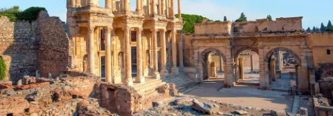 Die Ruinen der antiken Stadt Ephesos mit Säulen-Gebäude, Rundbögen und historischen Strukturen im Sonnenlicht.