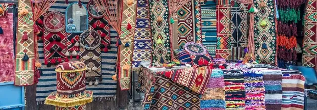 Marktstand mit bunten Teppichen und Wandbehängen auf einem traditionellen Markt in Kairo.
