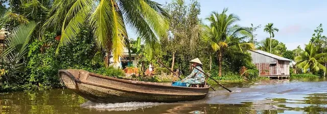 Vietnamese steuert traditionelles Holzboot über den Fluss Mekong