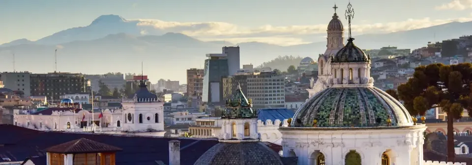 Panoramablick am Morgen auf die Stadt Quito mit Jesuitenkirche und Vulkan Cotopaxi im Hintergrund.