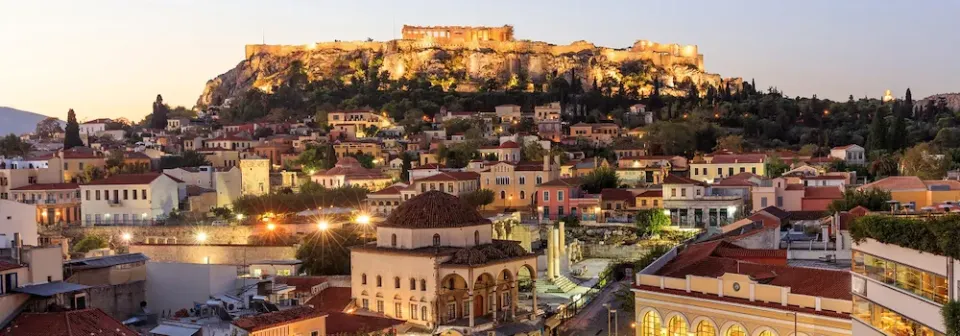 Panorama der Stadt Athen bei Sonnenaufgang mit dicht bebauten Häusern und der Akropolis auf einem Hügel.