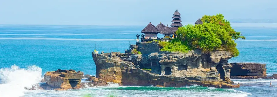 Die Tempelanlage Tempel Pura Tanah Lot auf einem Felsen in Bali, umgeben von türkisfarbenem Wasser.