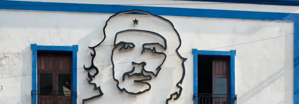 Bild von Che Guevara an der Fassade eines Hauses mit zwei Fenstern und blauen Fensterrahmen.