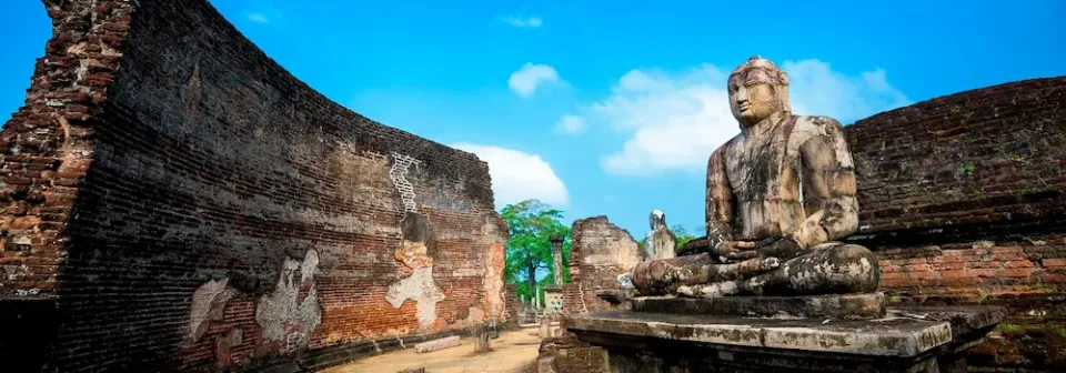 Eine alte Buddha-Statue in der Ruine des Polonnaruwa Tempel umgeben von historischen Mauern.