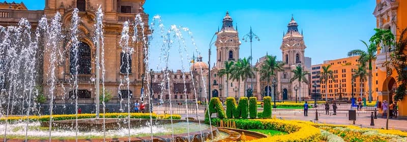 Blick auf Plaza de Armas mit Springbrunnen und die Kathedrale von Lima an einem sonnigen Tag.