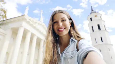 Auf dem Kathedralenplatz in der Altstadt von Vilnius lächelt eine junge Frau in die Kamera.