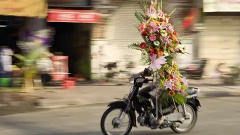 In Saigon ist das Treiben immer bunt und alles wird auf Vespas oder Mofas transportiert, so auch Blumen.