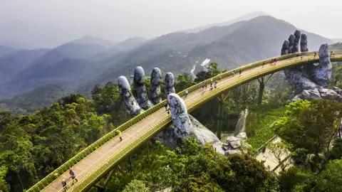 In den Bergen Zentralvietnams schreiten junge Traveller ab 35 gemeinsam über die spektakuläre Golden Bridge.