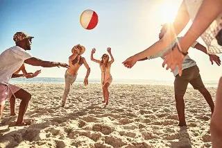 Eine Gruppe von Freunden, die an einem sonnigen Strand mit einem Ball spielen.