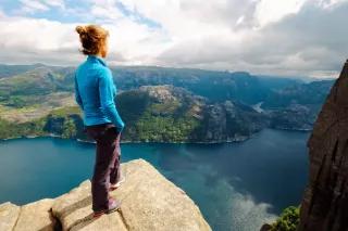 Eine Frau steht auf einem Felsen und schaut auf das Wasser.