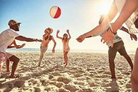 Eine Gruppe von Freunden, die an einem sonnigen Strand mit einem Ball spielen.