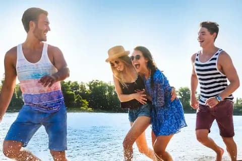 Vier fröhliche Personen am Wasser.