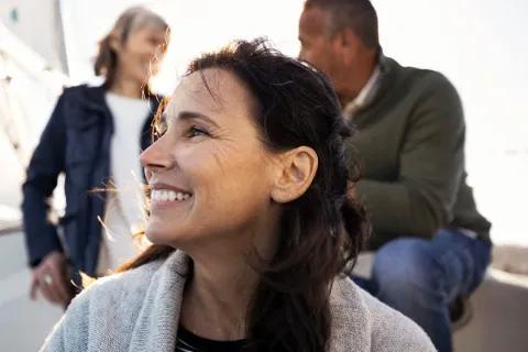 Eine lächelnde Frau genießt die Zeit auf einem Boot mit Freunden.