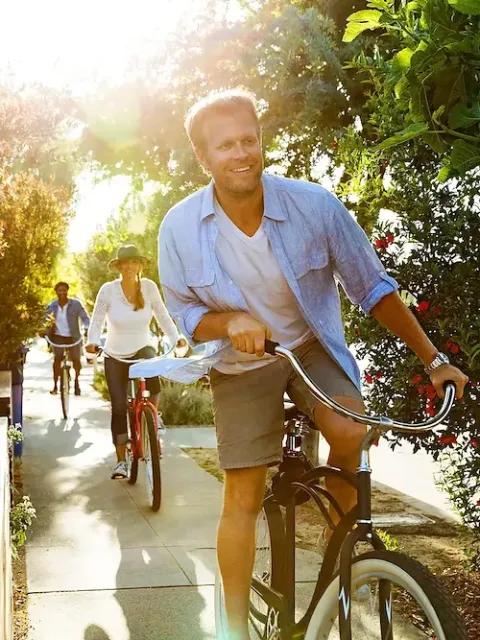 Drei glückliche Personen fahren auf dem Fahrrad auf einem asphaltiertem Weg