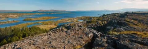 Panoramablick auf die Landschaft im Thingvellir Nationalpark mit Seen, Bergen, üppiger Vegetation und Felsen.