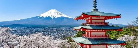 Schneebedeckter Berg Fuji mit einer roten japanischen Pagode und Kirschblüte im Vordergrund.