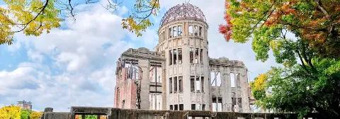 Die Ruine im Friedenspark in Hiroshima, umgeben von grünen Bäumen.