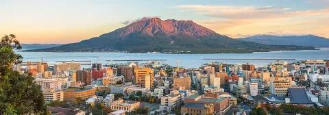 Panoramablick auf Stadt Kagoshima und das Meer und die Insel mit dem Vulkan Sakurajima im Hintergrund.