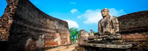 Eine alte Buddha-Statue in der Ruine des Polonnaruwa Tempel umgeben von historischen Mauern.