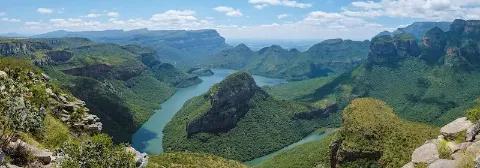Ausblick über di grünen Berghänge des Blyde-River-Canyon unter leicht bewölktem Himmel