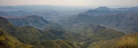 Weite Landschaft der grünen Drakensberge bei bewölktem Himmel