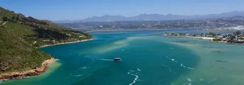 Lagune am Meer nahe der Stadt Knysna mit türkisblauem Meer und bewaldetem Ufer