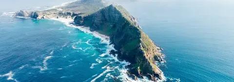 Luftaufnahme vom Kap der Guten Hoffnung in Südafrika mit türkisblauem Wasser und grünen Klippen.
