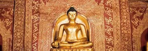 Goldener Buddha vor einer golden verzierten, roten Wand im Tempel Wat Phra Sing in Chiang Mai.