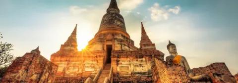 Buddhistischer Tempel Wat Yai Chai Mongkol mit Buddha-Statue aus Stein und Chedi-Bauten im Sonnenuntergang.