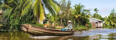 Vietnamese steuert traditionelles Holzboot über den Fluss Mekong