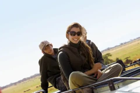 Eine Gruppe von Menschen lächelt fröhlich während einer Safari-Tour in der Wildnis.