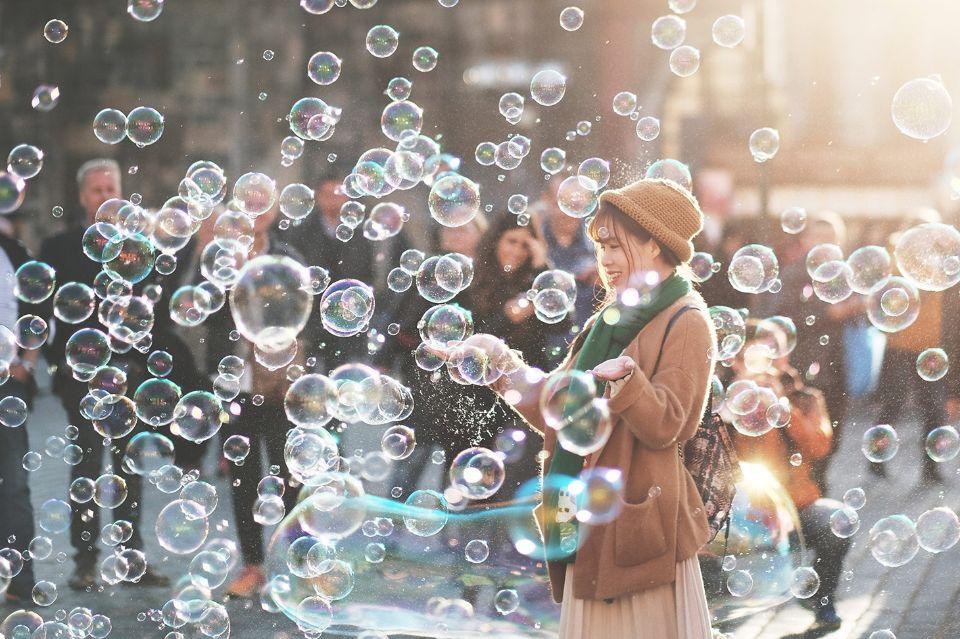 Eine Frau mit einem Hut, die Seifenblasen in der Luft fängt.