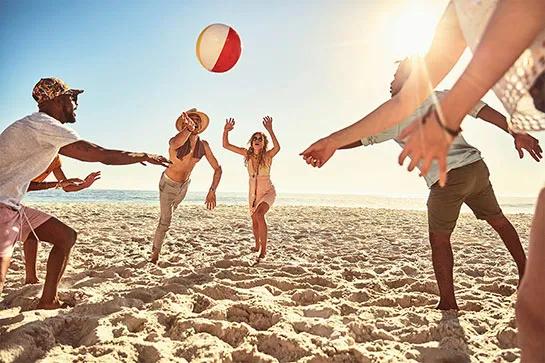 Eine Gruppe von Freunden, die an einem sonnigen Strand mit einem Ball spielen.