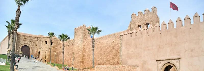 Personen laufen auf asphaltiertem Weg entlang der hohen Stadtmauer