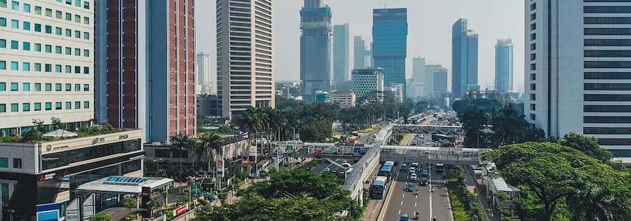 Autobahn mit Autos führt durch die Stadt Jakarta umgeben von zahlreichen Hochhäusern.