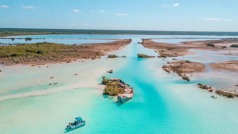 Die Laguna de Bacalar, auch „Lagune der sieben Farben“ genannt, zeigt verschiedene Türkis- und Blautöne bei blauem Himmel.