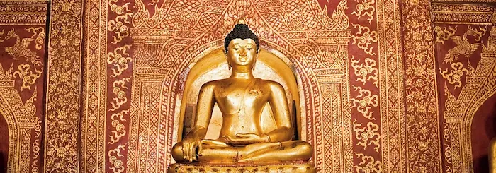 Goldener Buddha vor einer golden verzierten, roten Wand im Tempel Wat Phra Sing in Chiang Mai.