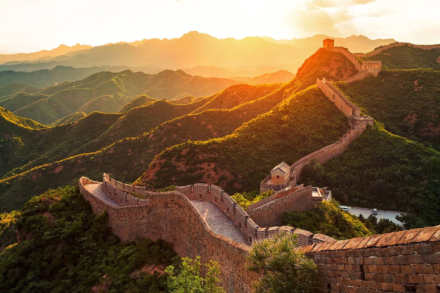 Die Chinesische Mauer und ihre hügelige Umgebung sind in der Abendsonne zu sehen.