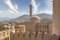 Auf Ihrer Reise durch den Oman sehen Sie den Turm des Forts, das höchste Gebäude in Nizwa. Der Blick schweift über die Neu- und die Altstadt, die Gärten und Lehmhäuser bis hinüber zu den Bergen.