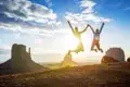 Junge Traveller springen freudig in die Luft vor dem Hintergrund des Monument Valley, ein Highlight dieser Rundreise durch den Westen der USA.