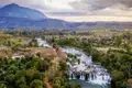 Dieser Panoramablick auf einen Fluss mit Wasserfällen, üppiger Vegetation und Bergen im Hintergrund auf dem Bolaven-Plateau begeistert uns auf unserer YOUNG LINE TRAVEL Rundreise druch Laos.