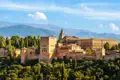 Auf Ihrer individuellen Rundreise im Mietwagen durch Andalusien haben Sie einen Panoramablick auf die Alhambra mit ihren Türmen, Mauern und Gebäuden, eingebettet in die Landschaft der Sierra Nevada.