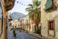 Fahnen geschmückte Straße in Lipari mit Palmen und traditioneller Architektur.