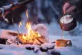 Aus einem ursprünglichen Kessel wird Kaffee in eine Holztasse neben einem romantischen Lagerfeuer gegossen. Vielleicht haben Sie auf Ihrer Reise nach Lillehammer in Norwegen auch die Gelegenheit ein solche Begegnung zu machen.