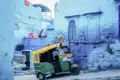 Ein buntes Tuk-Tuk steht in einer Gasse mit blau getünchten Häusern in Jodhpur, ein typischer Anblick bei der Stadterkundung in Jodhpur.